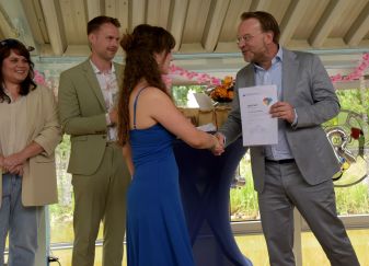 Schulleiter überreicht einer Absolventin der BG22 das Abschlusszeugnis mit Handschlag.