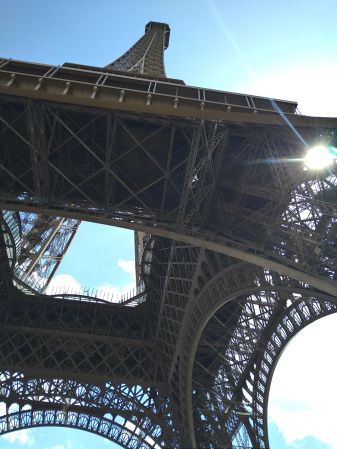 Blick von unten auf die filigrane Stahlkonstruktion des Eiffelturms in Paris bei sonnigem Himmel